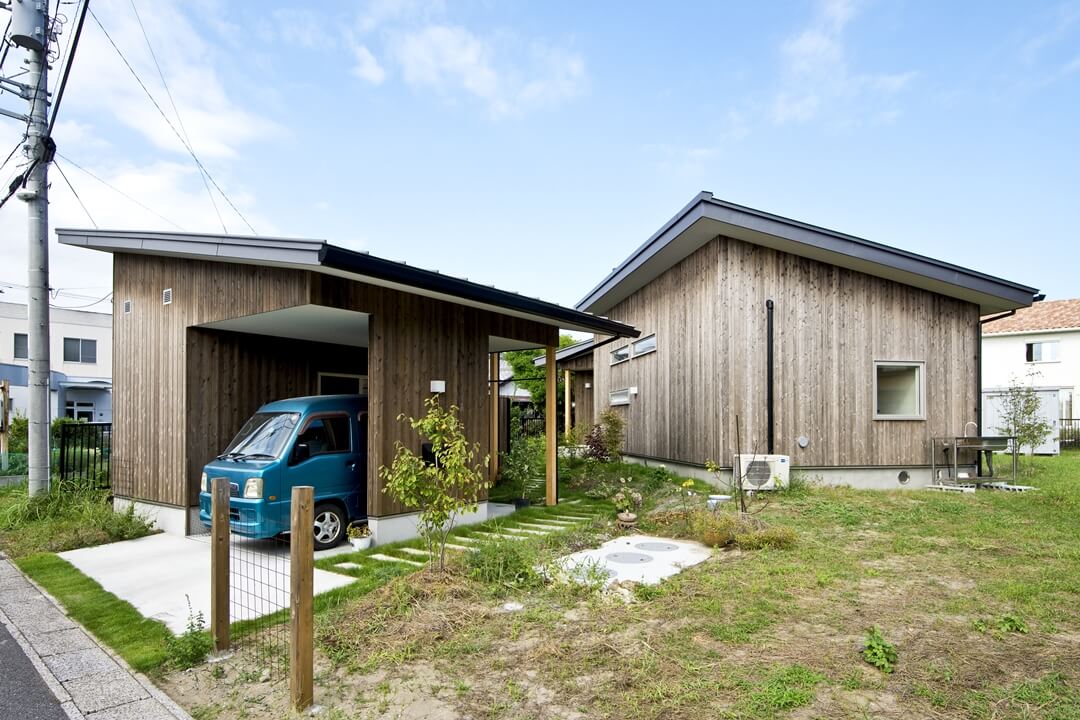 手前が納屋とガレージ、右奥が住まいです。ガルバリウム鋼板の屋根、屋久島の杉板張りは共通